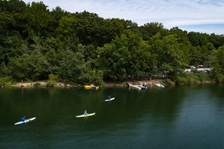 paddleboards and kayaks paddling towards a dock on a reservoir