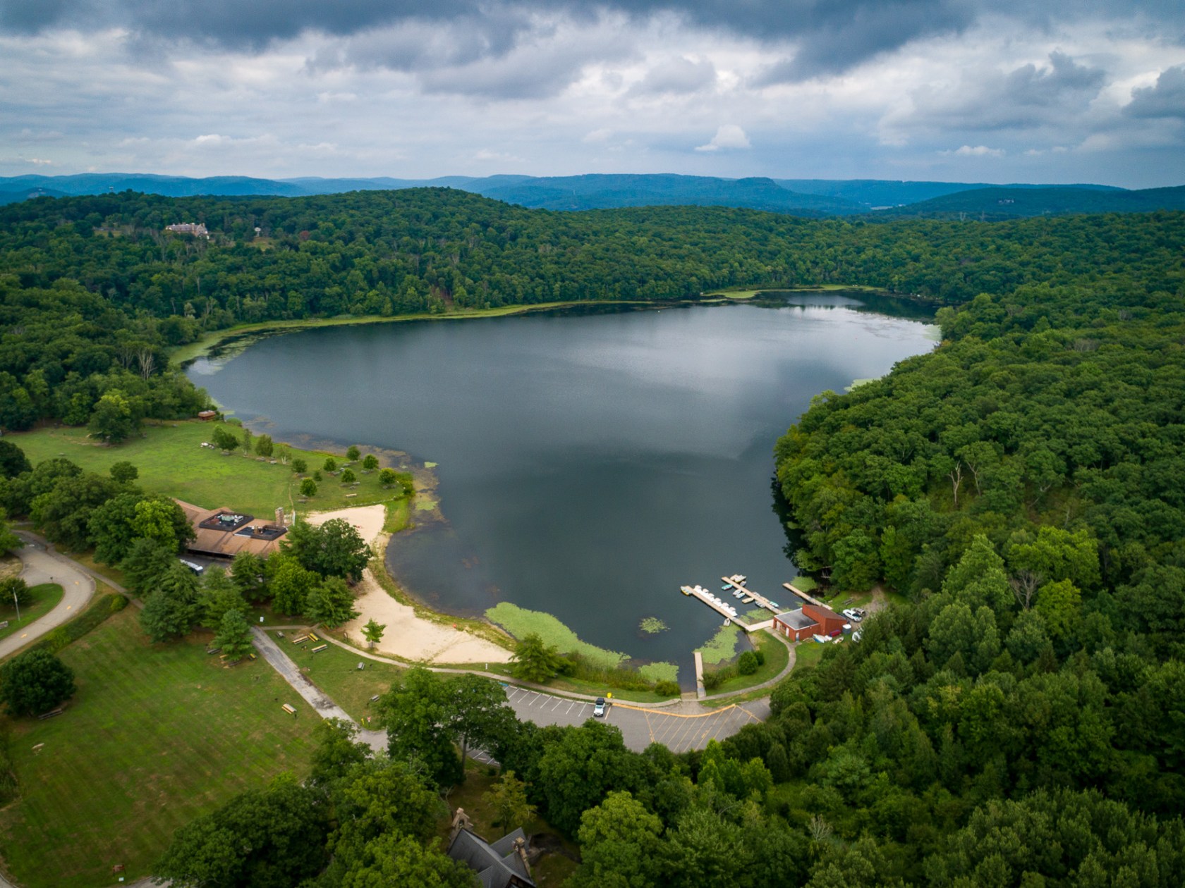 a large body of water surrounded by trees and a boathouse with docks
