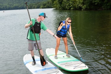 Two people on paddle boards, the instructor is pointing at the other person's paddle
